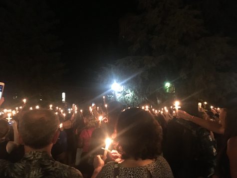 Members of the community gather during the candlelight vigil and raise candles and phones to show their support. Photo credit: Kayla Fitzgerald