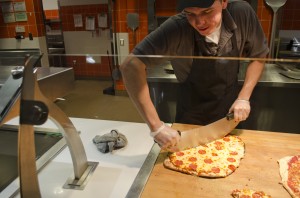 Photograph by Mozes Zarate Vincent Fuentes, senior business major, prepares a pizza at Sutter Dining.