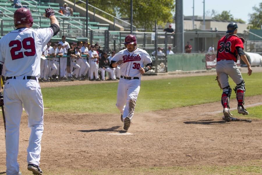 Ryne Clark (left) looks for a high five from Jake Bailey (right) after he scores a run during Sundays game against the CSU East Bay Pioneers. Photo credit: Grant Mahan