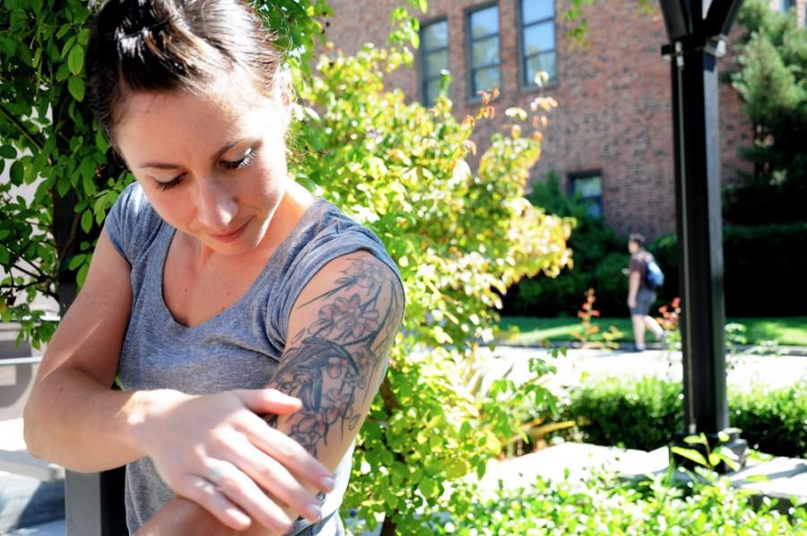 Jenny Barker, graduate student of kinesiology and exercise physiology, takes a study break to show off her tattoo by Selvester’s Cafe-by-the-Creek. Photo credit: Annie Paige