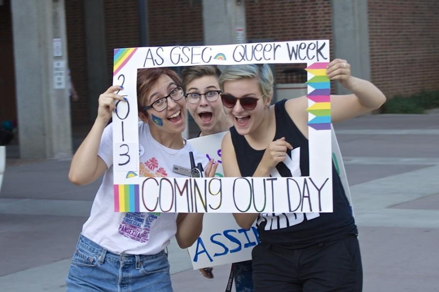 Emilee Hunt, Rachel Ward and Alex Dooley pose with a National Coming Out Day frame. 