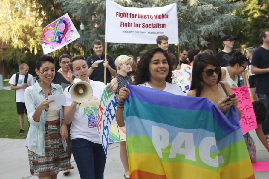 Students hold signs during the Pride March to show support for Queer Week.