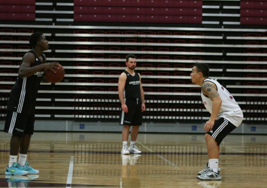 Chico State basketball player Jalen McFerren, left, sets up the offense with guard Mike Rosaroso, right, playing defense. Photo credit: John Domogma