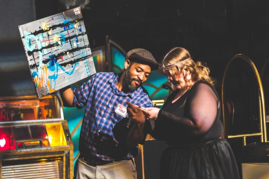 Artist Mazi Noble checks the winning raffle ticket for his donated art piece, valued at $75, during the Rent Party in the Performing Arts Center. Photo credit Trevor Yale Ryan
