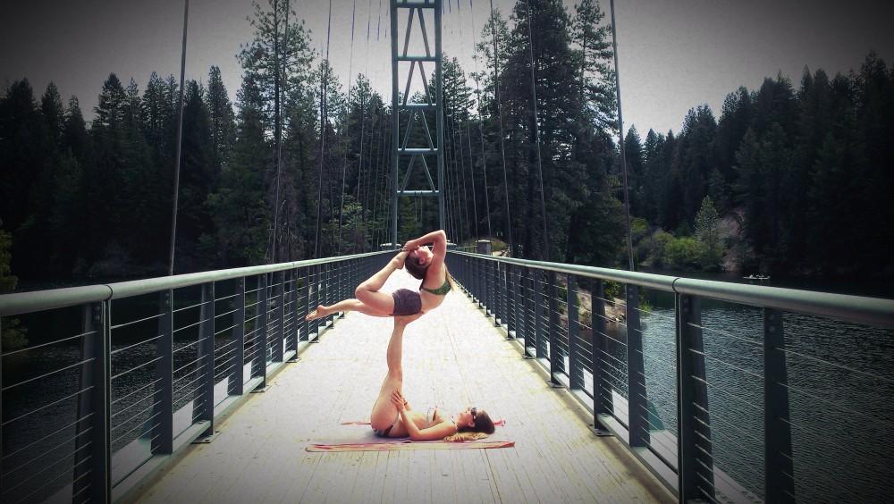 Maggie Berrier holds a difficult position on a bridge near the water of Mt. Shasta with help from her fellow AcroYoga friends. Photo courtesy of Maggie Berrier.
