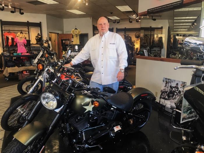 Stephan Adams poses with new bikes in his Harley Davidson store Photo credit: Elizabeth Helmer