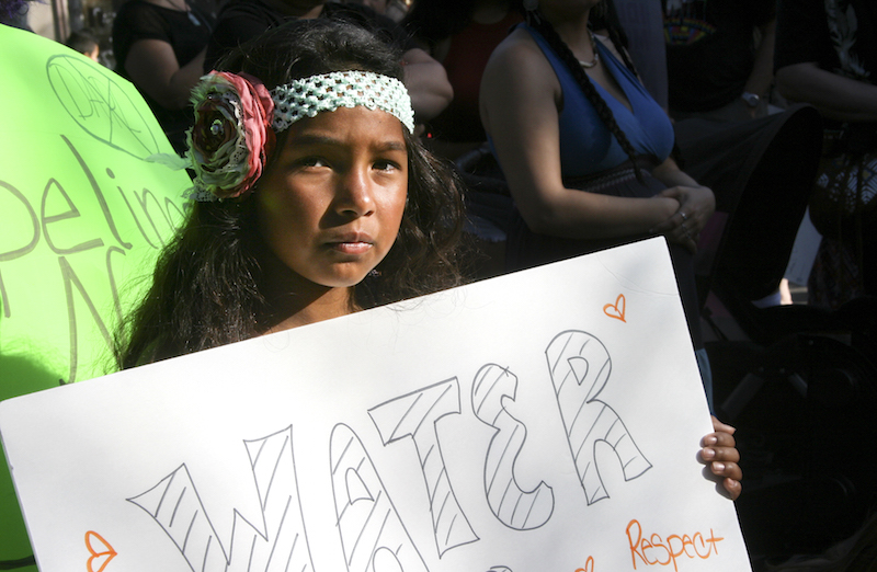 Milan Pete, 10, stands in solidarity with a sign that reads Water is Life. Photo credit: Bianca Quilantan