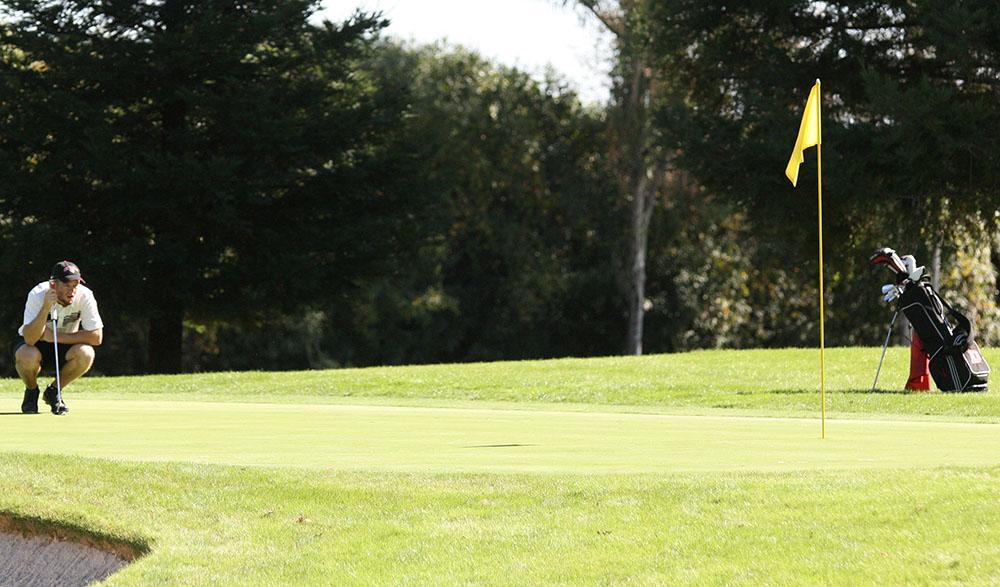 A Chico State golfer examines the green before taking a putt. Photo credit: John Domogma