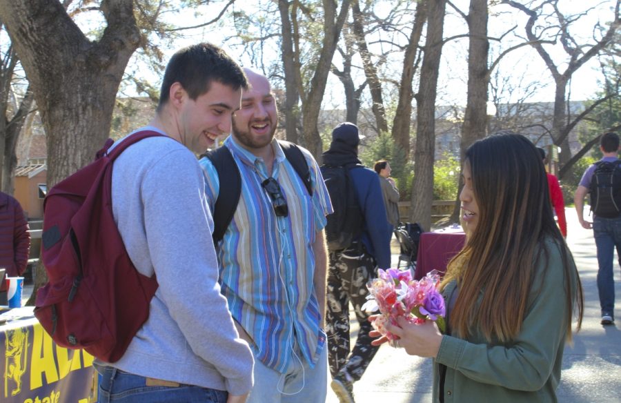 On a sunny February morning, Briana Vazquez of Delta Sigma Pi offers Valentines Day grams to a couple of curious passerbys on near Plumas Hall. Photo credit: Anne Chamberlain