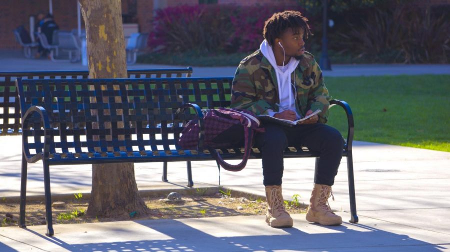 Nathaniel Nevels writes rhymes as he enjoys the sunshine at Chico State on Thursday. Photo credit: Carly Maxstone