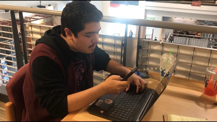 While doing his homework, Fernando Salas started getting distracted and picked up his phone. Photo credit: Karen Limones