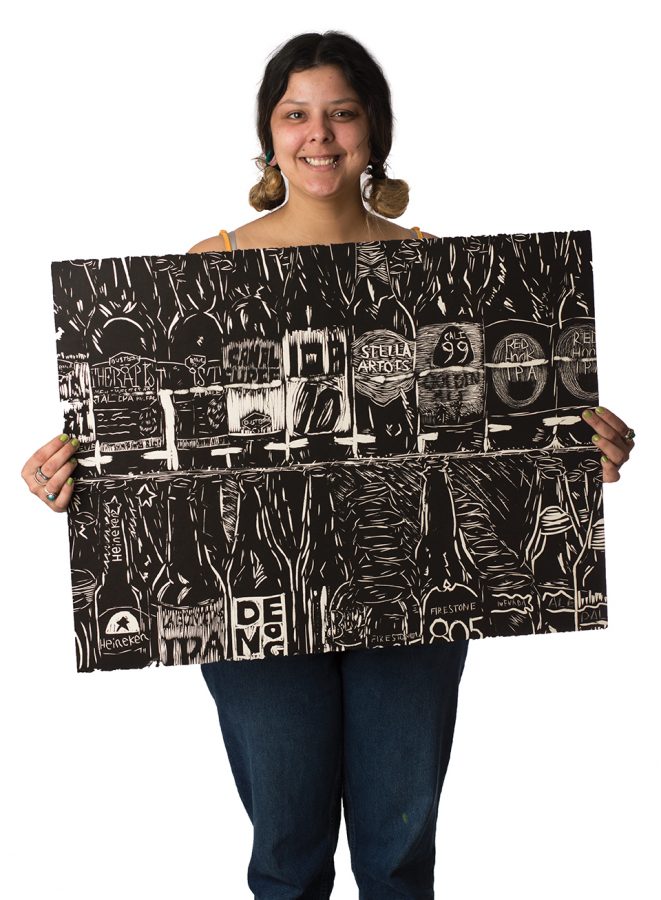 Marisa Sergovia holds up one of her paintings. Photo credit: Sean Martens
