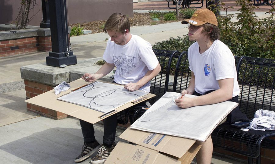 Eli Grusin, left, and Tyler Munstock, right, draw the Ring Roll sculpture on campus as part of an art class on March 29. Photo credit: Martin Chang