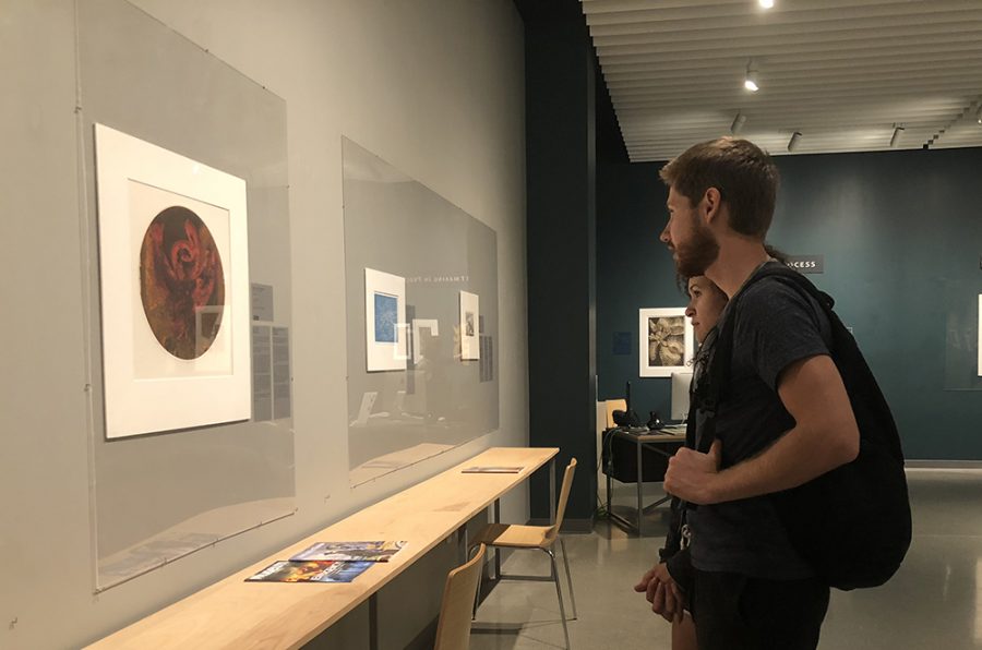 Simon Halland and Sophia Zoller admire some of the work showcased at Imagining the Past at the Janet Turner Print Museum. Photo credit: Alex Coba