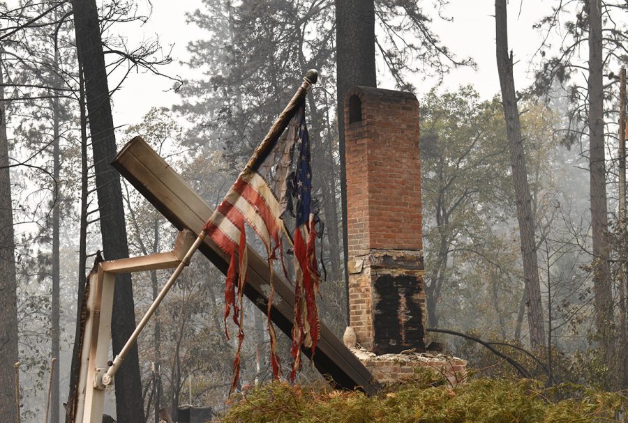 A flame-shredded American flag hangs on a mostly burnt piece of wood on Wildwood Lane in Paradise. Photo credit: Alex Grant