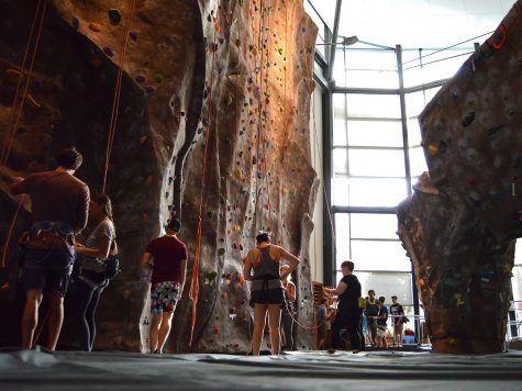 Students get prepared with their harnesses and look at the different rock climbing courses to choose from the one they want to attempt to climb to reach the top. Photo credit: Olyvia Simpson