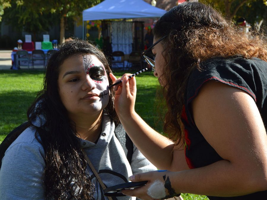 Dellanira Carrillo has half of her face painted like a sugar skull by Saidi Montoya in Trinity Commons on Friday. Check out this story and more on this weeks newscast. Photo credit: Olyvia Simpson