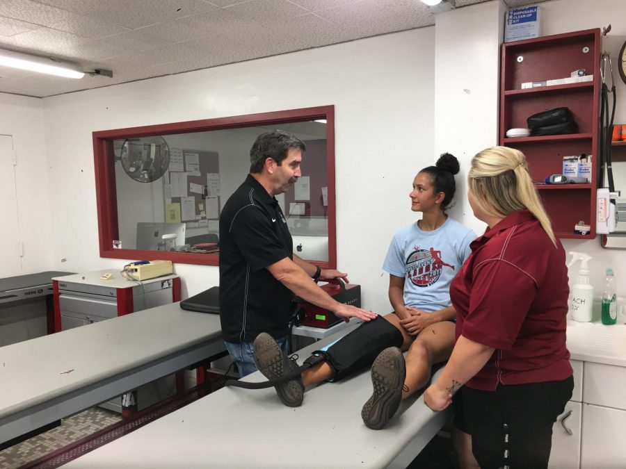 Head athletic trainer Scott Barker working with an athlete alongside his assistant, Halie Hall Photo credit: Karina Cope