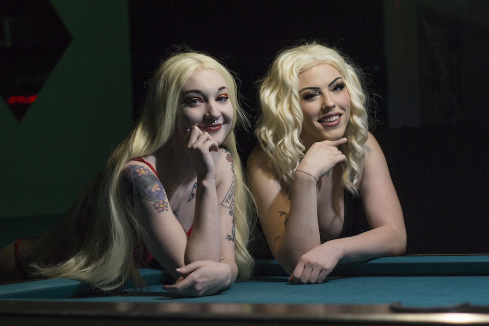 Sapphire (left) and Scarlett (right) are two of Centerfolds' dancers are smiling and posing in front of a pool table. Photo credit: Brian Luong
