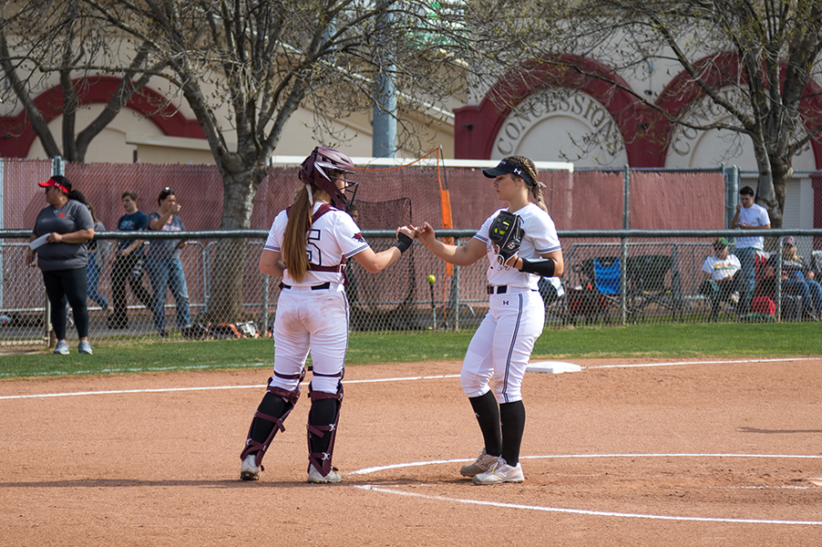 #15 catcher Sara Mitrano (left) gives #14 pitcher Brooke Larsen (right) a fist pump in a softball game at Chico State (Ryan McCasland/Chico State Sports Information)