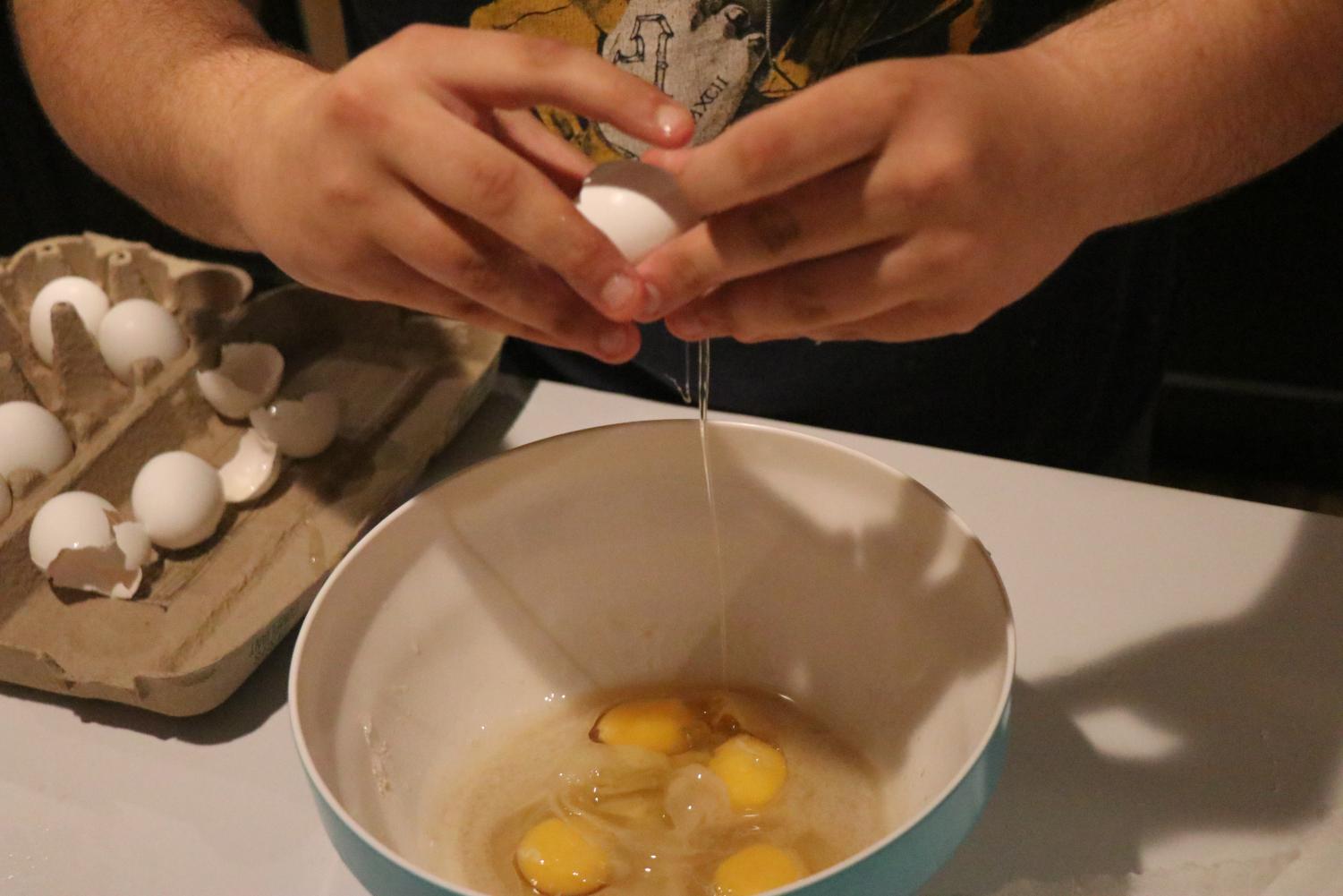 eggs being cracked into bowl with bread ingredients
