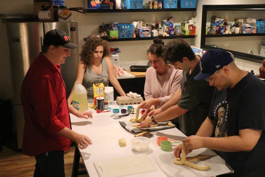 Students and Hillel director braiding challah on white table
