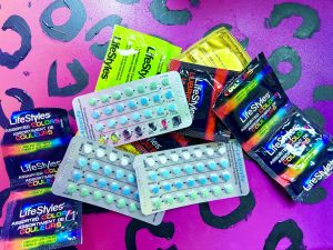 Condoms and birth control pills with purple cheetah print background