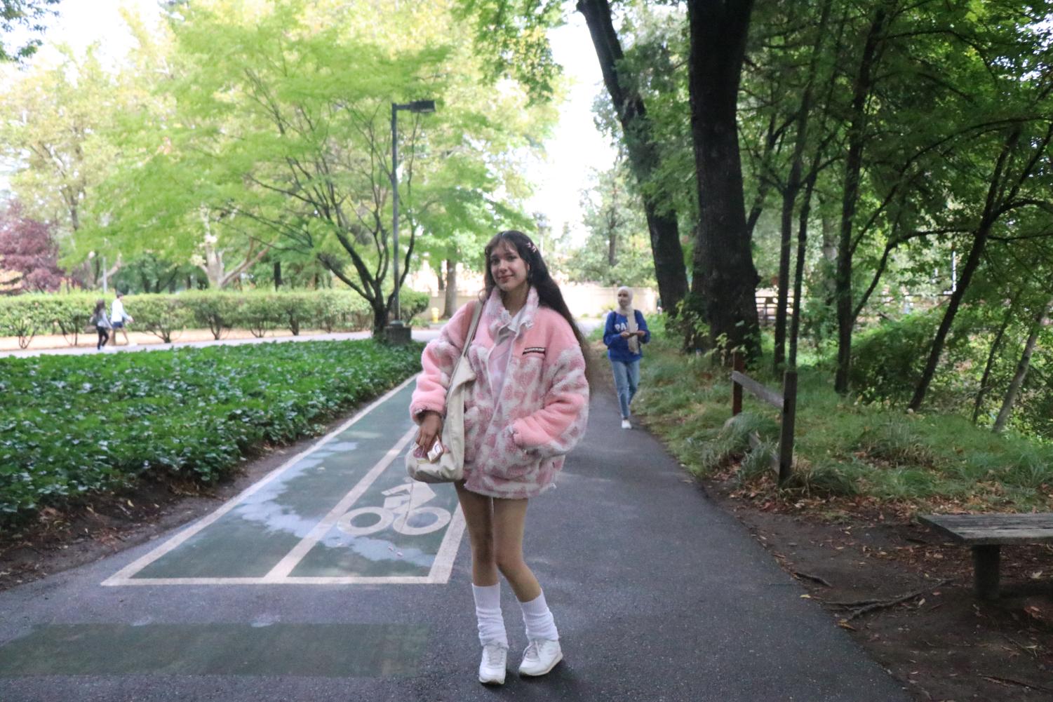 student walking through wooded part of campus in fluffy pink garb