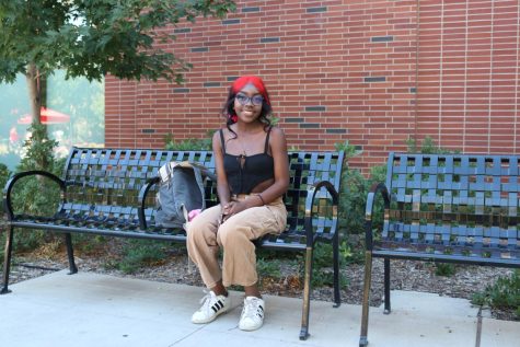 Student sitting on bench smiling in a stylish outfit