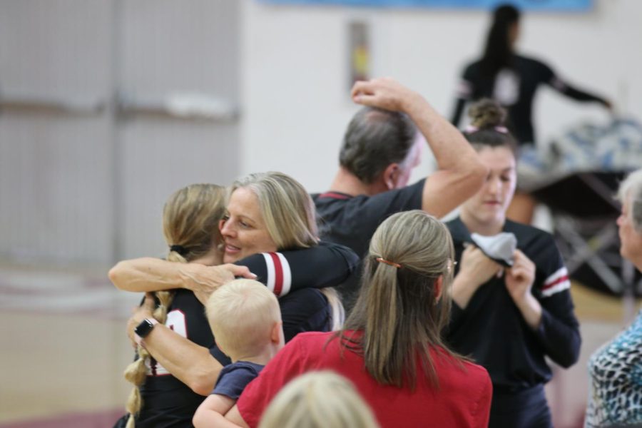 volleyball players hugging and chatting with parents after game