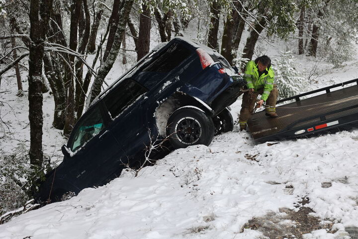 Man in neon green jacket attempting to get car out of deep snow crash