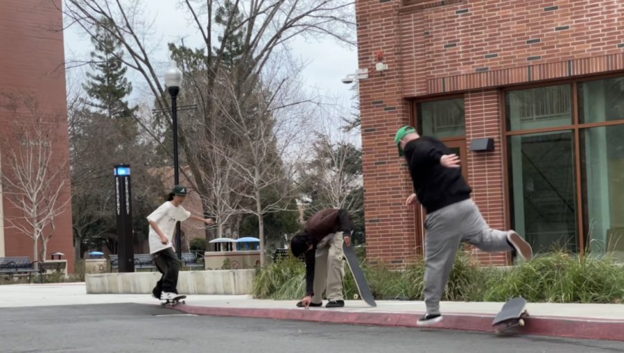 Three people skating outside of a brick building