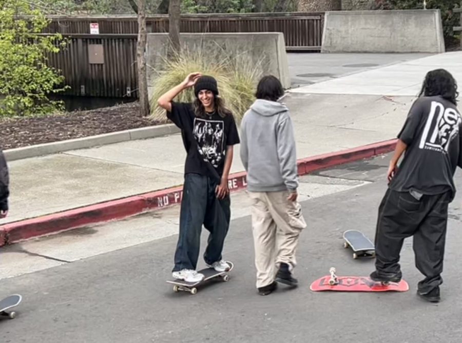 Three boys with skateboards. Two are facing away while one is facing the camera