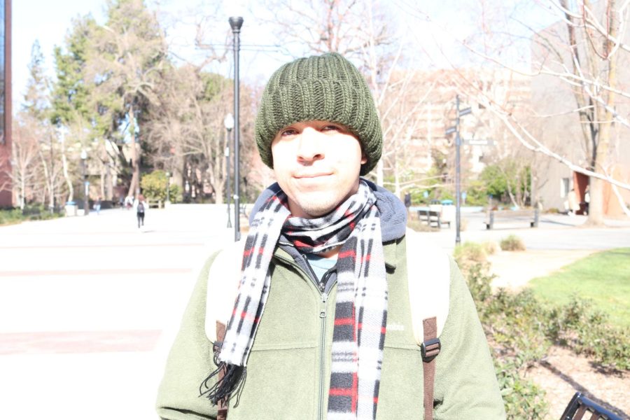 man with a green beanie and green jacket standing outside.