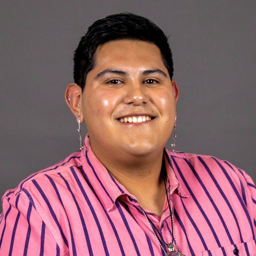 Chris Navarrete wearing a pink shirt with blue strips with a gray background.