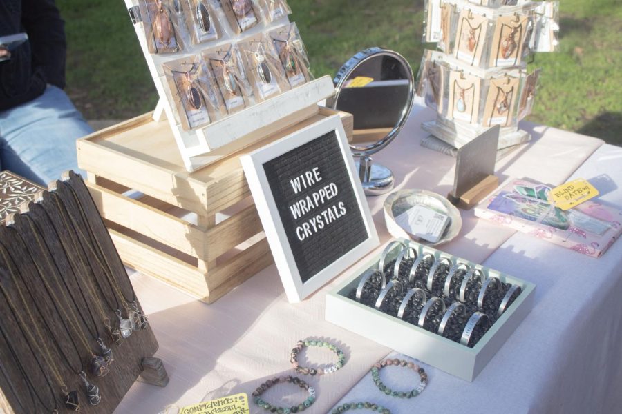 A white and black square frames the words "Wire Wrapped Crystals" sits in the middle of a table displaying different types of jewelry for sale.