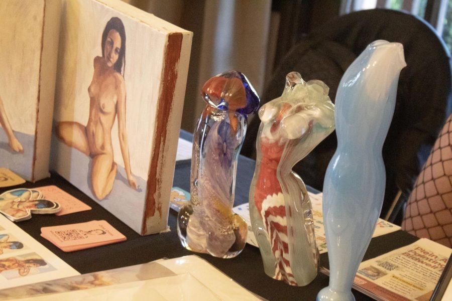 A painted canvas sits to the left of three multi-colored marble/stone nude busts and penis.