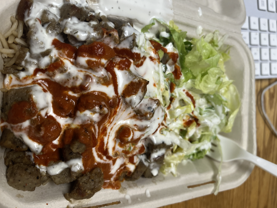Lamb sits on-top of rice and next to lettuce.