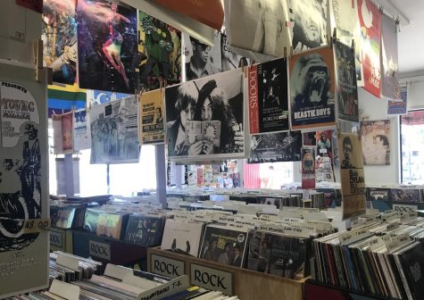 Interior of Melody Records, there are many rows of records with colorful posters hung over them.
