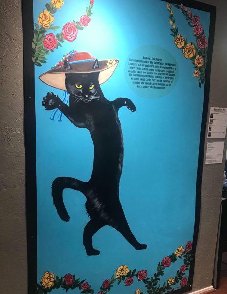 A very dapper black cat is painted on a blue background on a wall of The Great Catsby.