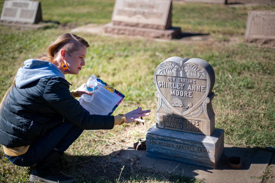 Chico State professor Sarah Gagnebin kneels next to a grave marker in the Chico Cemetery. Taken by Chico State photographer Jason Halley.