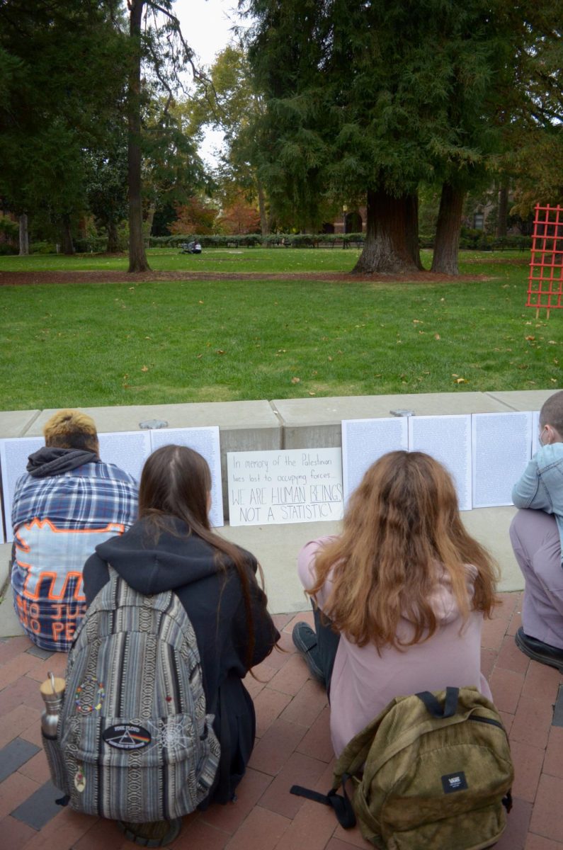 Students kneel on the sidewalk to read about Palestinian victims.
