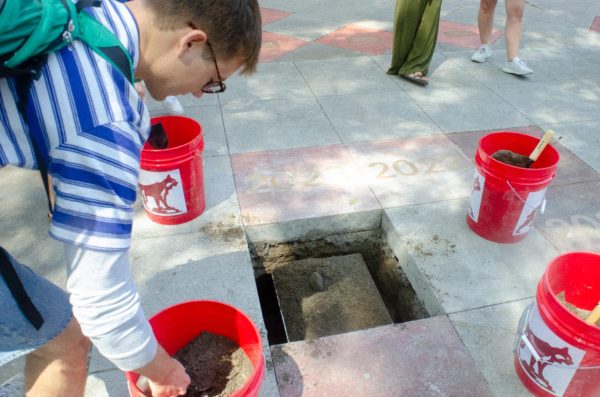 A student shovels dirt over the 2024 time capsule outside of Kendall Hall. The time capsule will be unveiled in 2074 as they are unveiled every 50 years. Taken by Grace Stark on April 23.