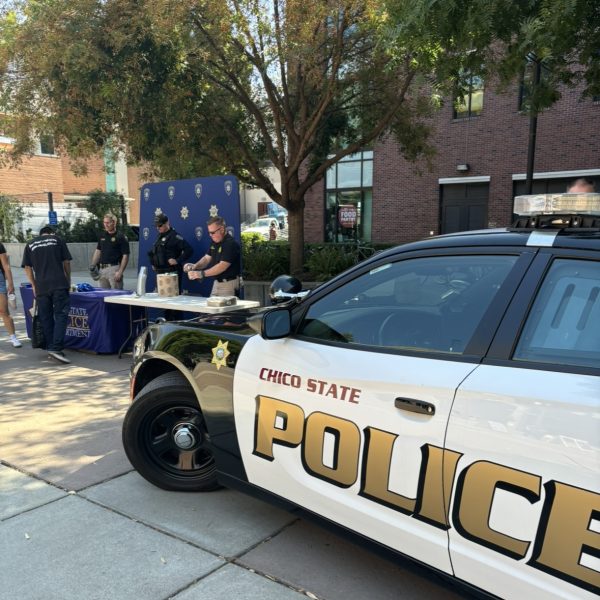 Chico State Police vehicle parked next to the display and root beer float table for the event. UPD is pictured setting up the floats at the tables behind the car. Taken by Sophia Mackinnon on Aug. 29.