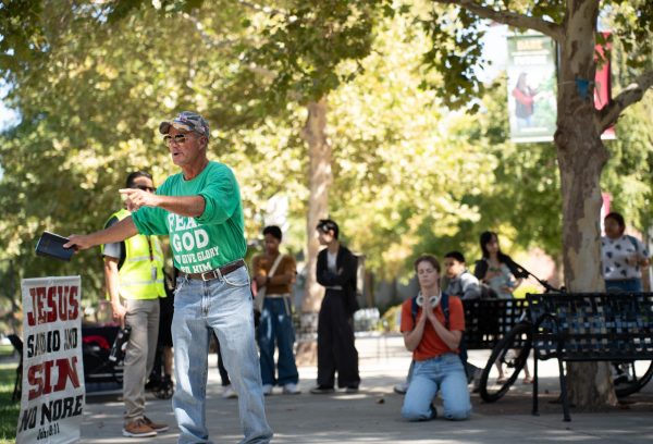 Second year student Anakin Hunter, right, disagrees with the speaker's message and prays after listening to him outside of the Bell Memorial Union at Chico State Tuesday, Sep. 24, 204.