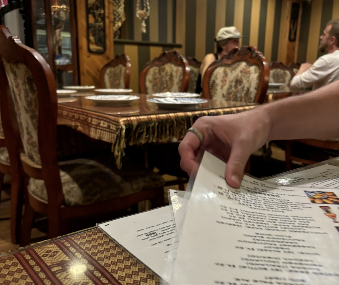 A customer grabbing a menu on a table inside the dining room of Chada Thai Cuisine. The room is large and many people were inside enjoying their dinner. This is in the far back of the restaurant. Taken by Sophia Mackinnon on Sept. 9. 