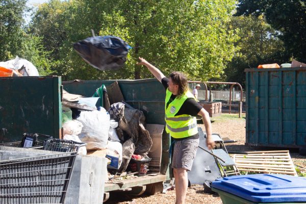 Volunteer Sage Hudson throws trash into the bin at Hooker Oak Park on Sept. 21. Hudson spent his birthday with friends and family helping clean up the community.