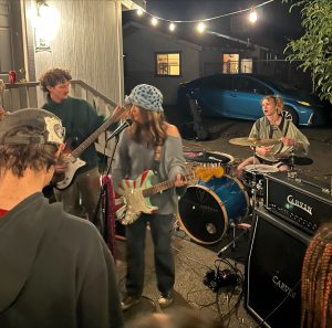 Ellie Stehr, James Pauly and Thistle Gardner of punk band D-VA prepare to close the night with their highly anticipated set as the crowd's favorite group at a lively backyard show featuring multiple performers. Photo taken by Adriana Carrera.