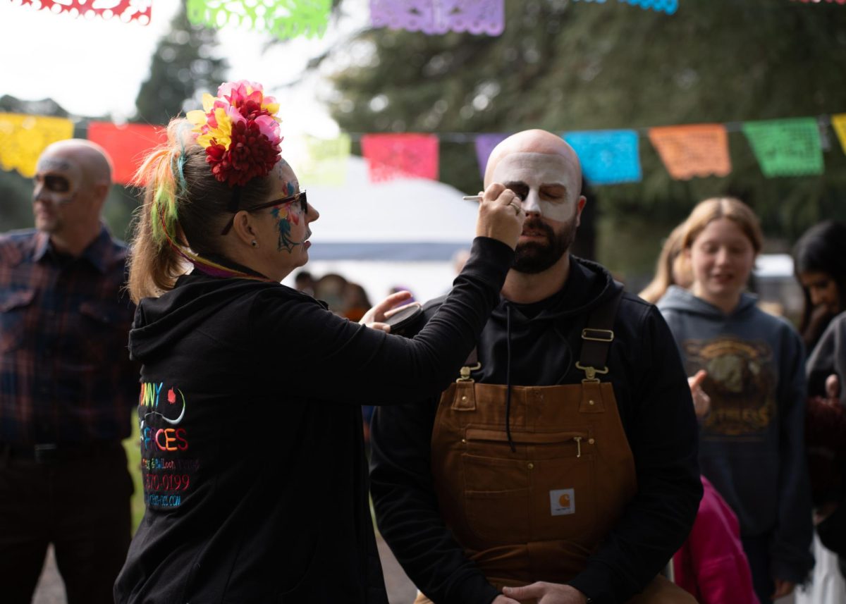 The Chico Cemetery hosted a Dia de Muertos event for the community Saturday Nov. 2, 2024. Jeni Borgman, left, painted Slide Tackle’s band member Chris Briggs’ face. Owner of Funny Faces Chico and with over 20 years of experience in face painting, Borgman said her sugar skull paintings honored those who have passed.