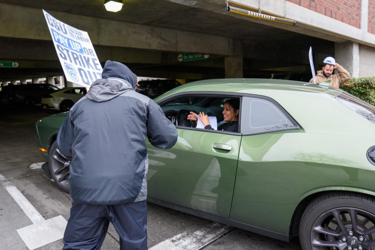 A member of the striking Teamsters Local 2010 union hands a flyer to a car entering the Cherry St. parking garage while picketing on Tuesday, Feb. 17, 2026 in Chico, Calif. The teamsters say the CSU system is exploiting a loophole in their contract to deny previously-promised raises.
(Dash Ferrero/The Orion)